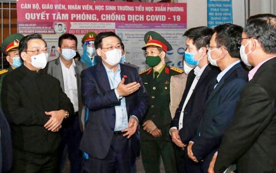 Secretary of Hanoi's Party Committee Vuong Dinh Hue (C) and Hanoi's leaders monitor the implementation of measures to prevent and control Covid-19 in Nam Tu Liem District. (Photo: SGGP)