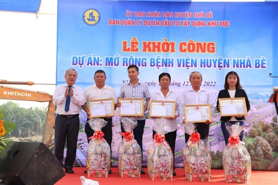 Secretary of the Party Committee of Nha Be District Duong The Trung (L) offers gifts to households who had good performances in handing over land to the expansion project of Nha Be District’s hospital. (Photo: SGGP)