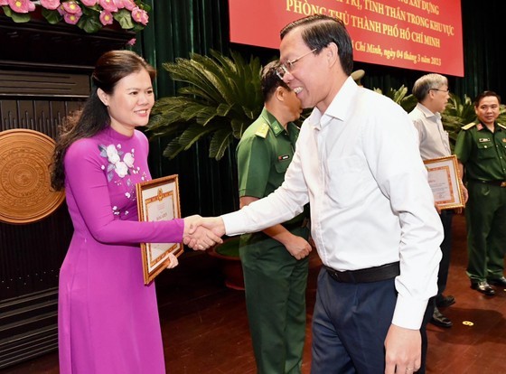 Chairman of the People’s Committee of the city Phan Van Mai (R) hands over certificates of merit to collectives. (Photo: SGGP)