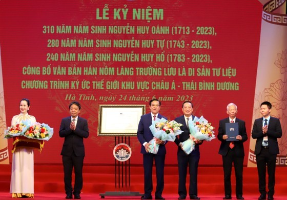 Deputy Minister of Culture, Sports and Tourism Hoang Dao Cuong offers a certificate of recognition and flowers to Ha Tinh Province and the Nguyen Huy family. (Photo: SGGP)