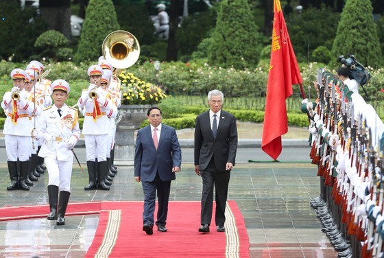 PM Pham Minh Chinh and his Singaporean counterpart Lee Hsien Loong walk on a red carpet at the welcome ceremony in Hanoi on August 28. (Photo: SGGP)