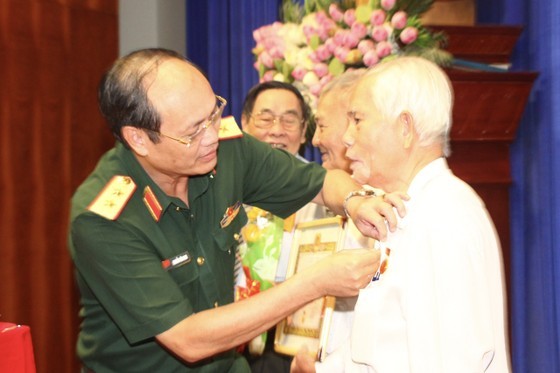 Commander of the HCMC High Command Lieutenant General Nguyen Van Nam (L) hands over Party membership badges to veteran Party members
