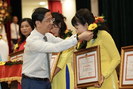 Standing Deputy Editor-in-Chief of the Sai Gon Giai Phong Newspaper Nguyen Thanh Loi offers cetertificates of merit to teachers. (Photo: SGGP)
