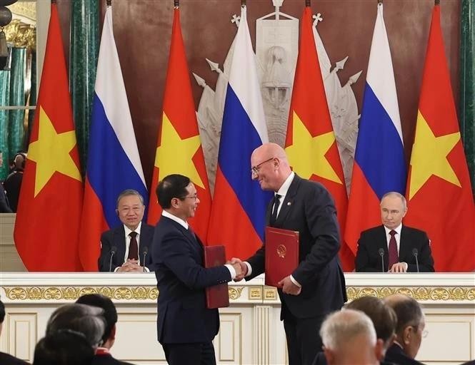 Party General Secretary To Lam and President Vladimir Putin witness Vietnamese Deputy Prime Minister and Minister of Foreign Affairs Bui Thanh Son (L) and Russian Deputy Prime Minister Dmitry Chernyshenko exchange the agreement on cooperation in the oil and gas sector and protocols governing the operations of the Vietsovpetro and Rusvietpetro joint ventures. (Photo: VNA) bui-thanh-son-chernyshenko-vna.jpg