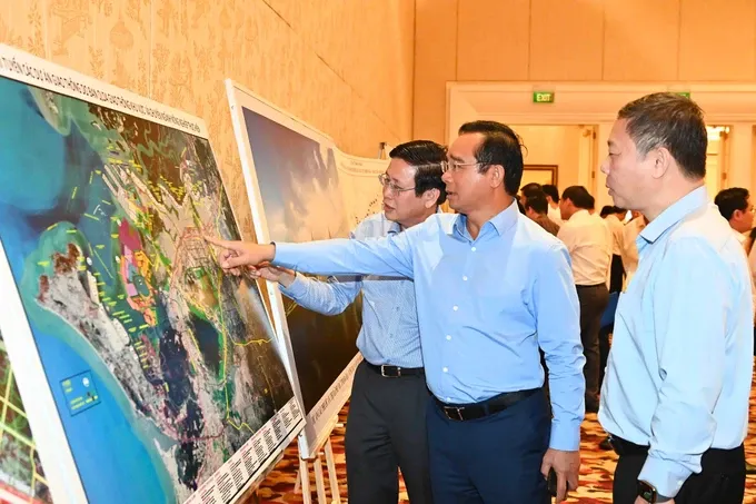 Chairman of the Ho Chi Minh City People's Committe Nguyen Van Duoc and delegates review a map of key projects across three localities. (Photo: SGGP) 3b9bd3306a57df098646-8512-550.jpg