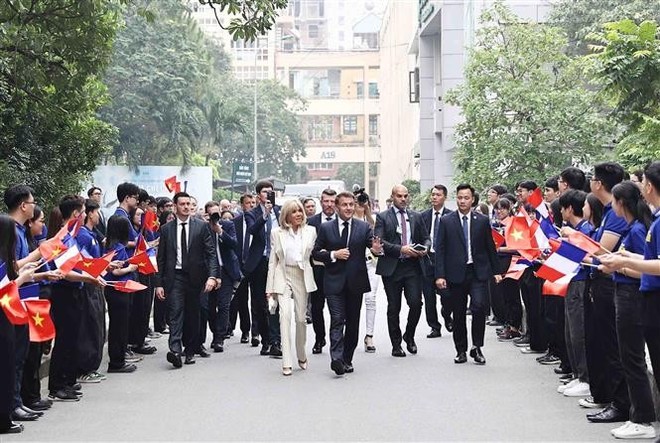 USTH students welcome French President Emmanuel Macron and his spouse. (Photo: VNA) vna-potal-tong-thong-phap-va-phu-nhan-tham-truong-dai-hoc-khoa-hoc-va-cong-nghe-ha-noi-8057324.jpg