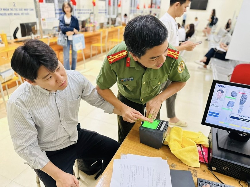 A police officer instructs a foreigner how to register for a level-2 electronic identification account. (Photo: VNA) 01072025thuyv14.jpg