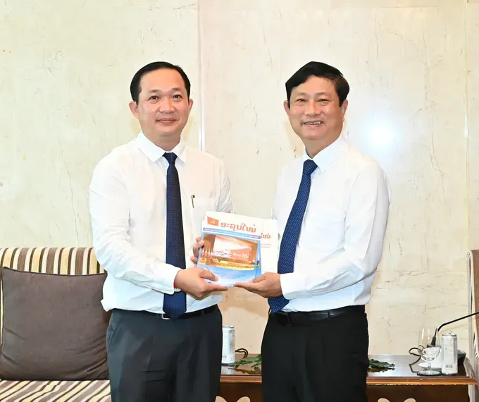 Editor-in-Chief of Alunmay Magazine, Vanlaty Khamvanvongsa offers the magazines to Chairman of the Ho Chi Minh City People's Council, Vo Van Minh (R). (Photo: SGGP) 4-6795-236.jpg