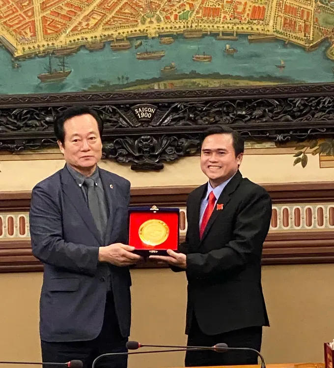 Mr. Yoon Tae-han, Chairman of the Welfare and Environment Committee (L) offers a gift to Head of the Culture and Social Affairs Committee of the Ho Chi Minh City People’s Council, Cao Thanh Binh. (Photo: SGGP) z7017000717585-e3ef4df5105bff415a0d4a800369b5aa-9683-7457.jpg