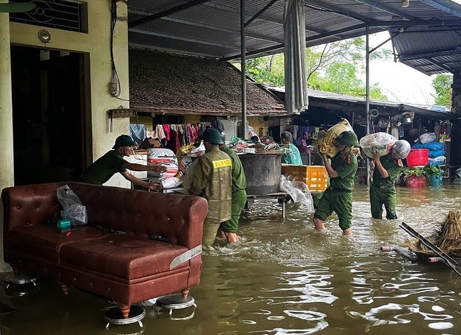 Police and security forces help people move their assets in a flooded area. (Photo: VNA) flood.jpg