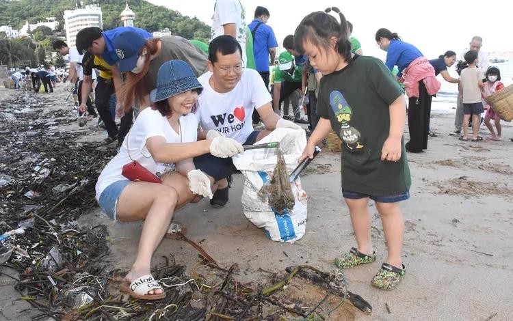 A family in Vung Tau joins the “Blue Sea” Club to help protect the marine environment. (Photo: SGGP) rac1.jpg