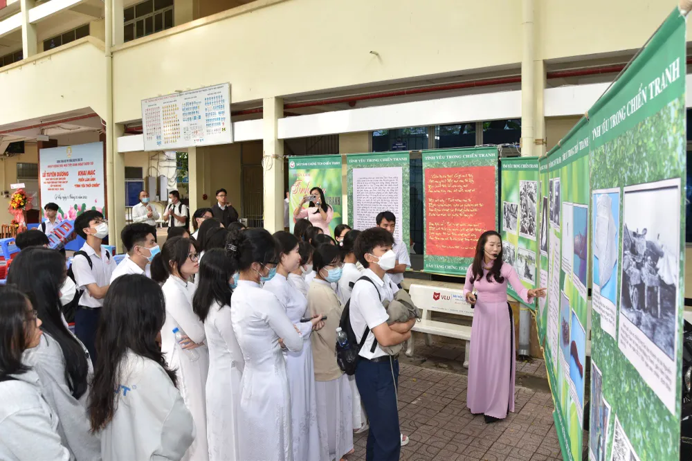 Học sinh chăm chú nghe hướng dẫn viên Bảo tàng Chứng tích chiến tranh giới thiệu về triển lãm ảnh