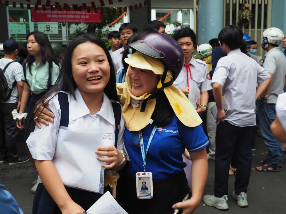Tranh thủ về sớm, một phụ huynh mặc nguyên đồng phục đi làm đón con tại điểm thi. Ảnh: THU TÂM z6678278796894_376b811e43dd487a33efc107bd410c50.jpg