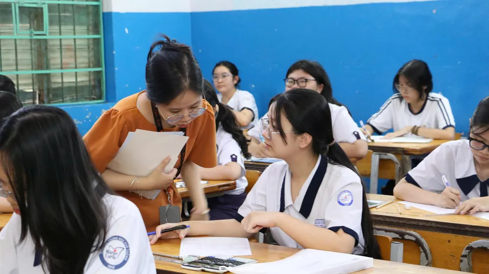 Cán bộ coi thi hướng dẫn thí sinh điền thông tin cá nhân vào giấy thi. Ảnh: THU TÂM z6744011304630_a3278d575702b359b791da75c6f3544f.jpg