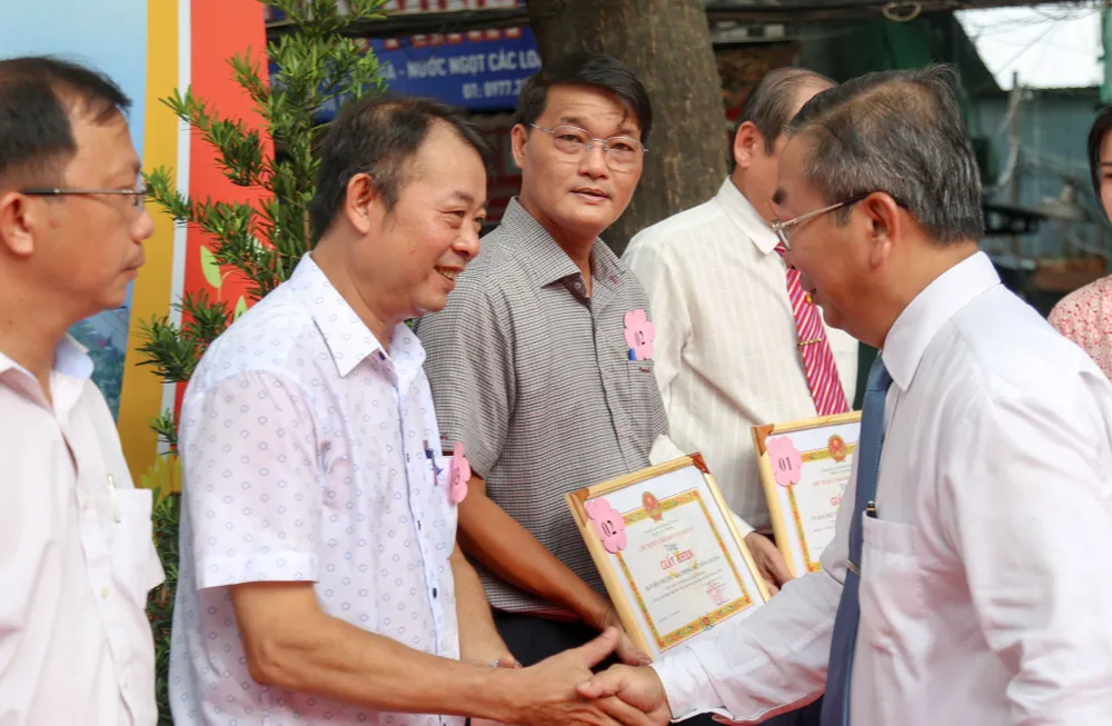 Bí thư Quận ủy quận 8 Võ Ngọc Quốc Thuận trao bằng khen cho hộ dân đồng thuận chủ trương. Ảnh: THẢO LÊ