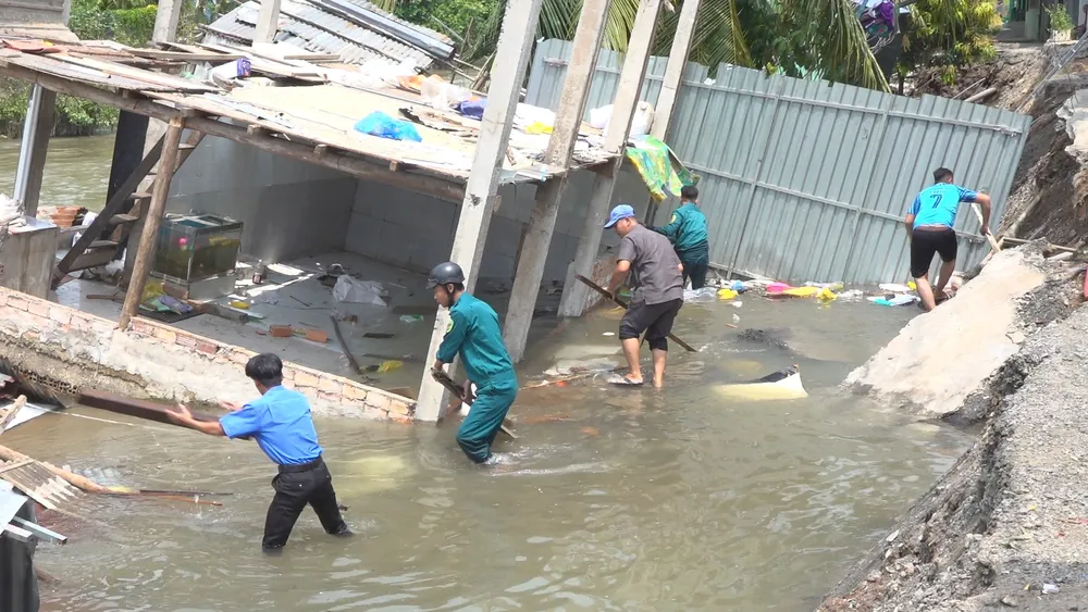 Các lực lượng hỗ trợ người dân di dời đồ đạc và triển khai các biện pháp khắc phục sạt lở. Ảnh: THANH NGHĨA