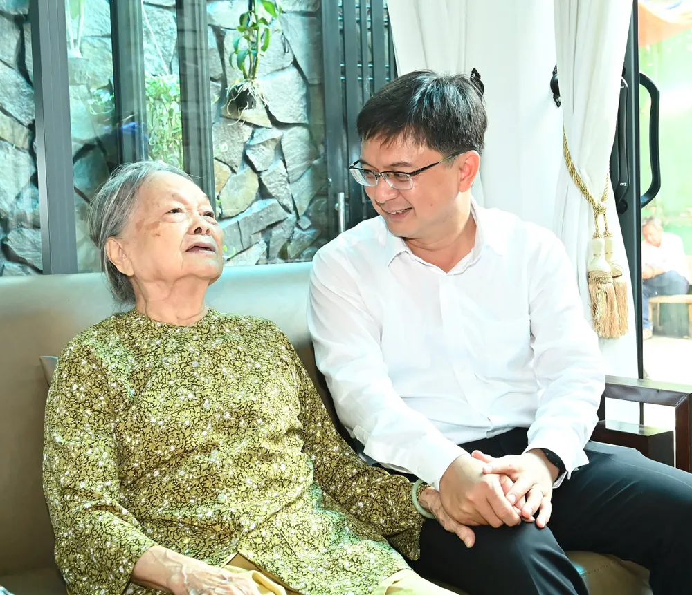 Đồng chí Nguyễn Mạnh Cường ân cần thăm hỏi sức khỏe bà Bùi Thị Anh. Ảnh: VIỆT DŨNG Bà Anh.jpg
