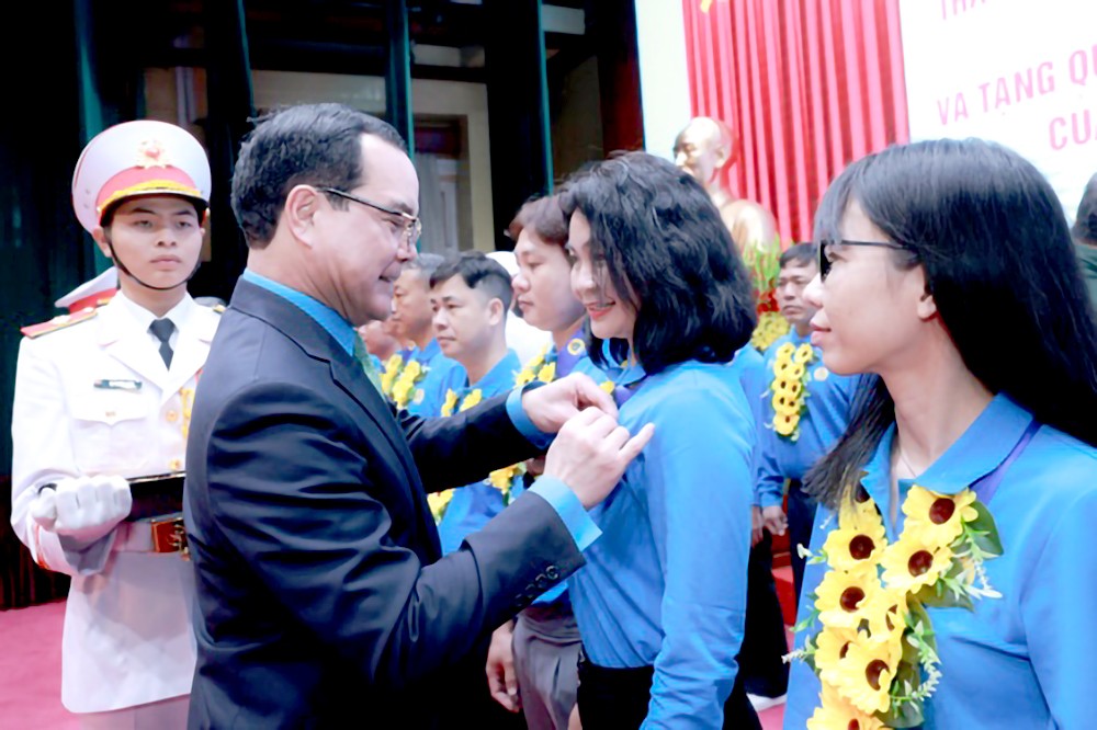 越南劳动总联团主席阮廷康给是模范工人-劳工的党员戴上胡伯伯徽章。