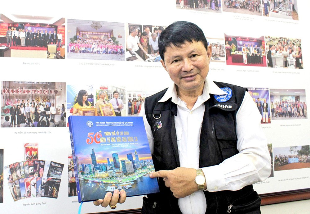 摄影师段怀忠与摄影集《胡志明市-50年英雄赞歌》。