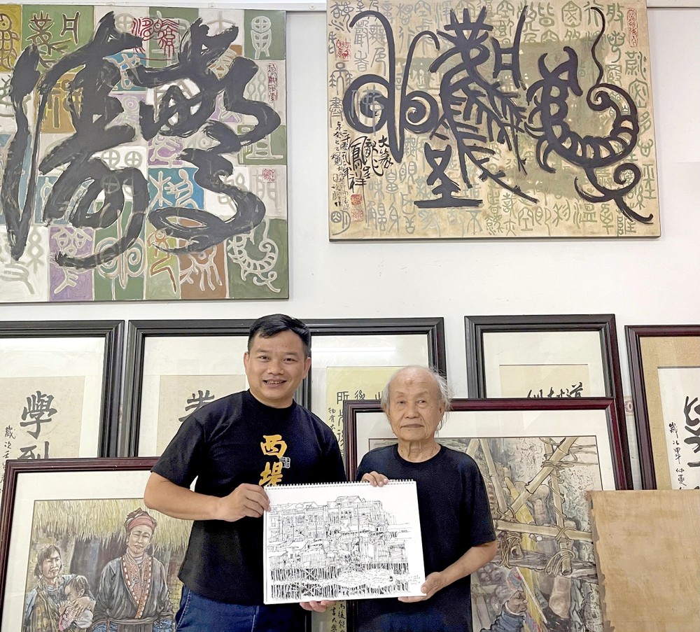 张路画家（右）向笔者赠送其写生集。