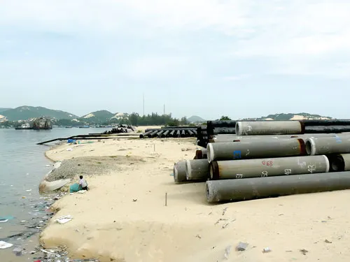 Cọc bê tông, cọc sắt nhập về chất ngổn ngang do dự án cảng trung chuyển bị đình trệ. Ảnh: V.Ngọc Cọc bê tông, cọc sắt nhập về chất ngổn ngang do dự án cảng trung chuyển bị đình trệ. Ảnh: V.Ngọc