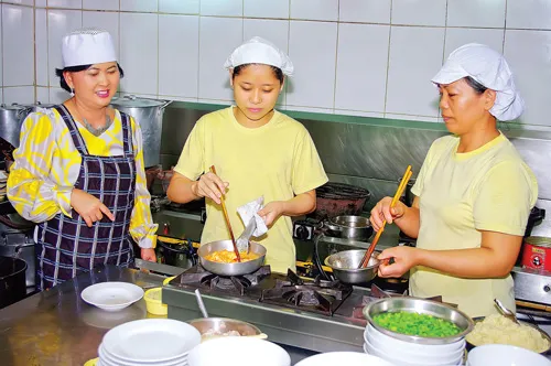 Bà Hoa (bìa trái) hướng dẫn chế biến các món ăn cho nhân viên.