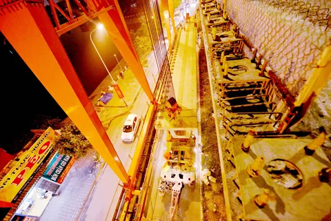 Việc thi công vẫn phải đảm bảo các phương tiện vẫn lưu thông bình thường bên dưới. Toàn cảnh khu vực lao dầm thuộc khu vực hồ Hào Nam. Phiến dầm sẽ được vận chuyển bằng xe chuyên chở đặc dụng tới vị trí lắp đặt. Cần cẩu chuyên dụng sẽ nâng phiến dầm lên trên mặt đường sắt. Dầm bê tông được cẩu ráp vào 2 trụ cầu giữa lòng hồ.