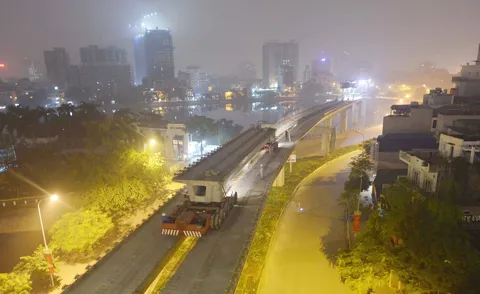 Việc thi công vẫn phải đảm bảo các phương tiện vẫn lưu thông bình thường bên dưới. Toàn cảnh khu vực lao dầm thuộc khu vực hồ Hào Nam. Phiến dầm sẽ được vận chuyển bằng xe chuyên chở đặc dụng tới vị trí lắp đặt. Cần cẩu chuyên dụng sẽ nâng phiến dầm lên trên mặt đường sắt. Dầm bê tông được cẩu ráp vào 2 trụ cầu giữa lòng hồ.