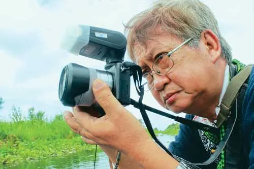 Đạo diễn, nhà văn Lê Văn Duy chụp ảnh quay phim ở nhiều tư thế khác nhau.