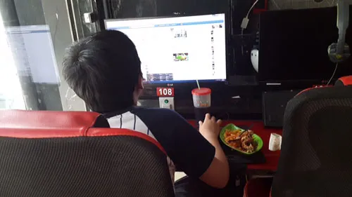 Một game thủ nhí tranh thủ ăn ngay tại chỗ chơi game.