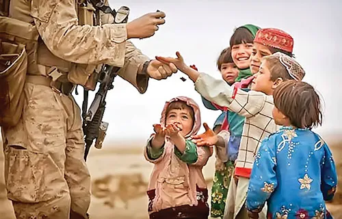 Một binh sĩ Hoa Kỳ đang phát kẹo cho các trẻ em Afghanistan tại một trạm kiểm soát ở Khan Neshin, tỉnh Helmand.
