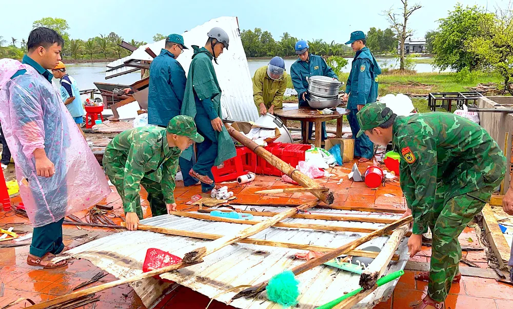 Cán bộ, chiến sĩ Đồn biên phòng Khánh Tiến cùng lực lượng Quân sự xã U Minh hỗ trợ hộ người dân che chắn lại nhà sau thiên tai. ẢNH: HOÀNG TÁ
