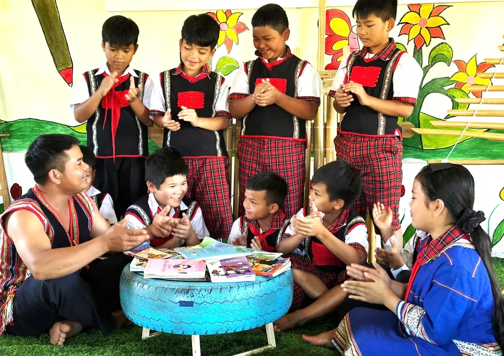 Anh A Áo (bìa trái) hướng dẫn học sinh ở xã Tu Mơ Rông, tỉnh Quảng Ngãi cách hát ting ting (Ảnh: THANH XIÊNG)