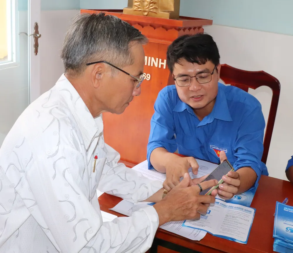 Nhân viên cấp nước hướng dẫn cài đặt ứng dụng chăm sóc khách hàng (app SAWACO CSKH) cho người dân ở cù lao Mỹ Khánh, xã Bình Khánh, TPHCM