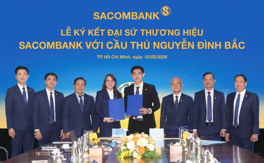 Cầu thủ Nguyễn Đình Bắc (phải) và bà Nguyễn Thị Kiều Anh (trái), Phó Tổng giám đốc SACOMBANK thực hiện nghi thức ký kết Thỏa thuận Đại sứ thương hiệu dưới sự chứng kiến của Ban lãnh đạo Ngân hàng