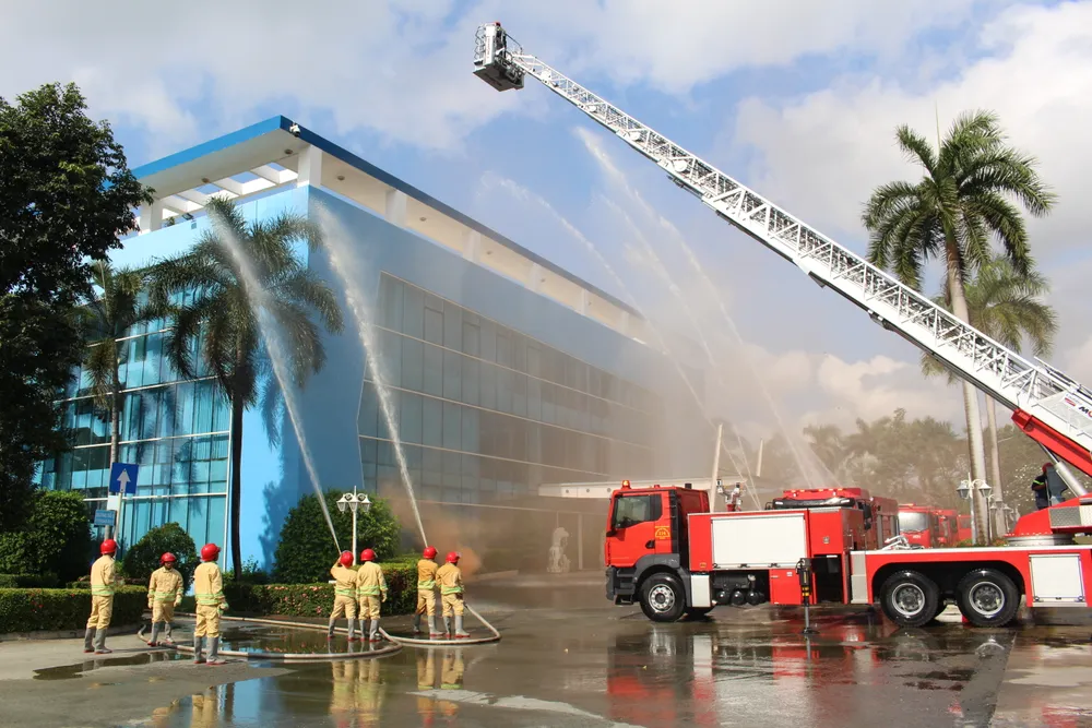 Lực lượng Cảnh sát PCCC-CNCH phối hợp với lực lượng PCCC cơ sở VWS triển khai phương tiện, phun nước từ xe thang trong tình huống diễn tập tại Khu liên hợp Đa Phước.