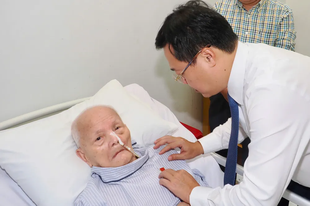 Đồng chí Lê Quốc Phong trân trọng cài Huy hiệu Đảng lên ngực áo đồng chí Nguyễn Duy Anh. Ảnh: HOÀNG HÙNG