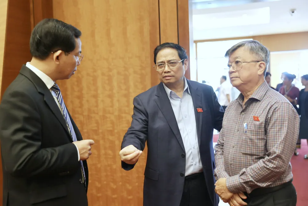 Thủ tướng Phạm Minh Chính (giữa) trao đổi với Chủ nhiệm Ủy ban Tài chính - Ngân sách của Quốc hội Lê Quang Mạnh (bìa trái) và đại biểu Trương Trọng Nghĩa (TPHCM) bên hành lang Quốc hội, sáng 24-5. Ảnh VIẾT CHUNG