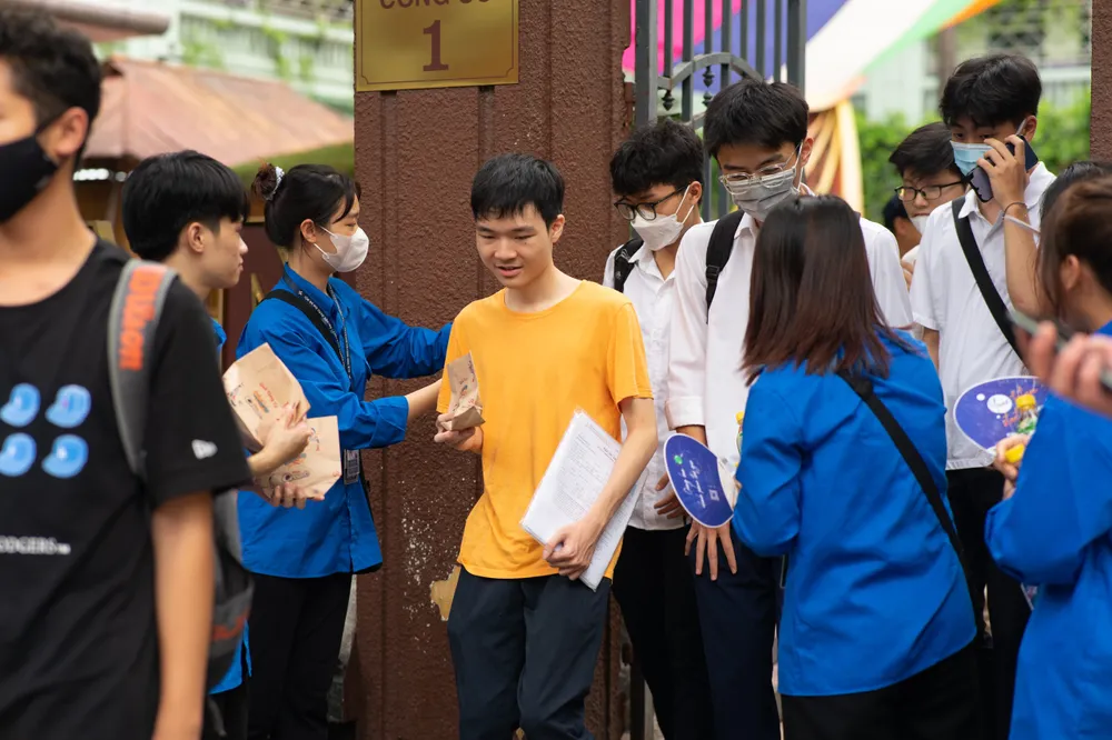 Thanh niên tình nguyện hỗ trợ thí sinh tại điểm Trường THCS-THPT Nguyễn Bỉnh Khiêm (Cầu Giấy, Hà Nội). Ảnh: HOÀNG DƯỠNG