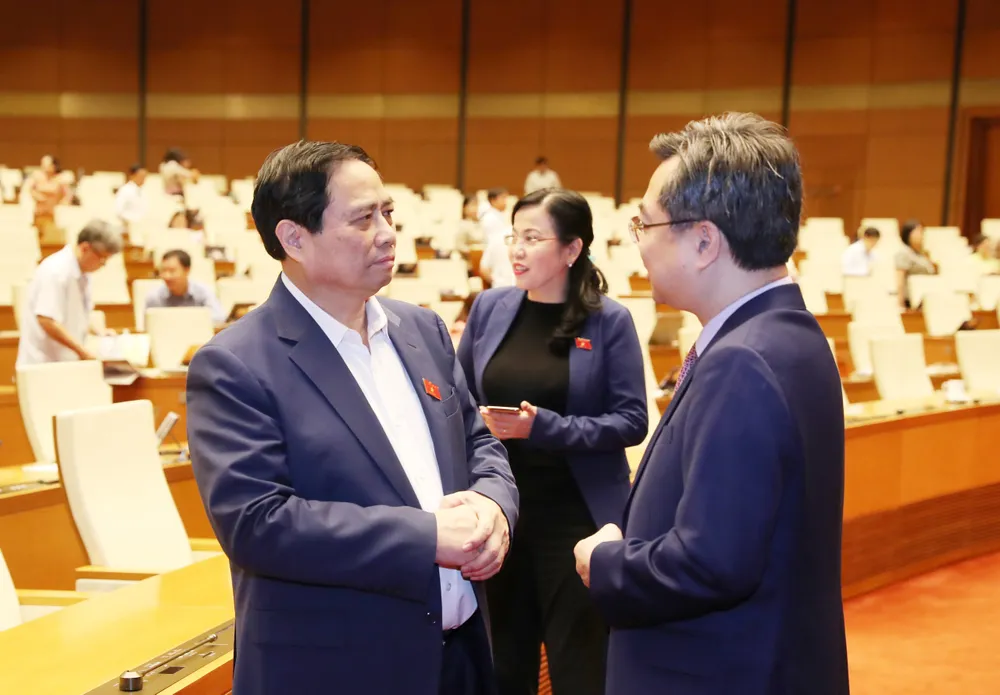 Thủ tướng Phạm Minh Chính trao đổi với Bộ trưởng Bộ Xây dựng Nguyễn Thanh Nghị tại phiên thảo luận ở hội trường về dự thảo Luật Kinh doanh bất động sản. Ảnh: QUANG PHÚC