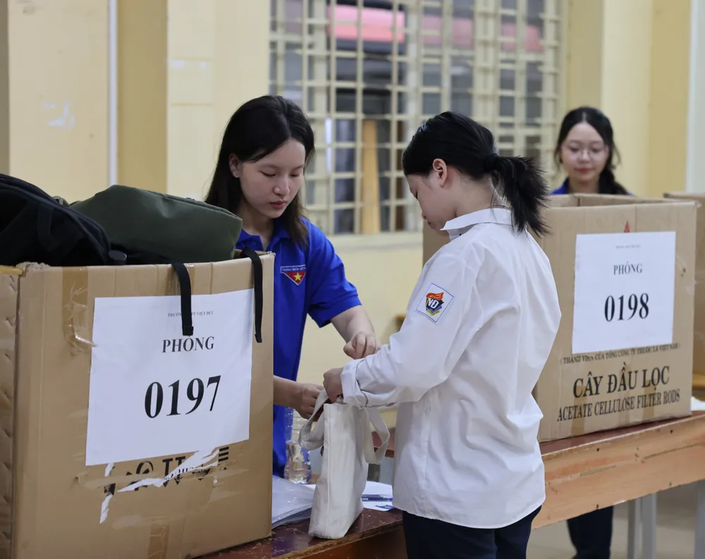 Sinh viên tình nguyện hỗ trợ thí sinh cất đồ đạc cá nhân tại điểm thi Trường THPT Việt Đức, quận Hoàn Kiếm, Hà Nội. Ảnh: QUANG PHÚC 