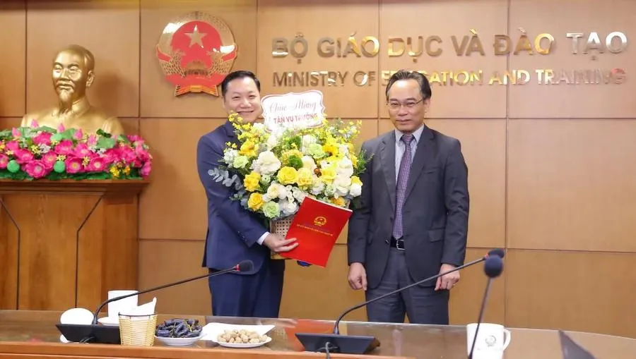 Thứ trưởng Bộ GD-ĐT Hoàng Minh Sơn (bên phải) trao quyết định và tặng hoa chúc mừng tân Vụ trưởng Vụ Giáo dục đại học Nguyễn Tiến Thảo