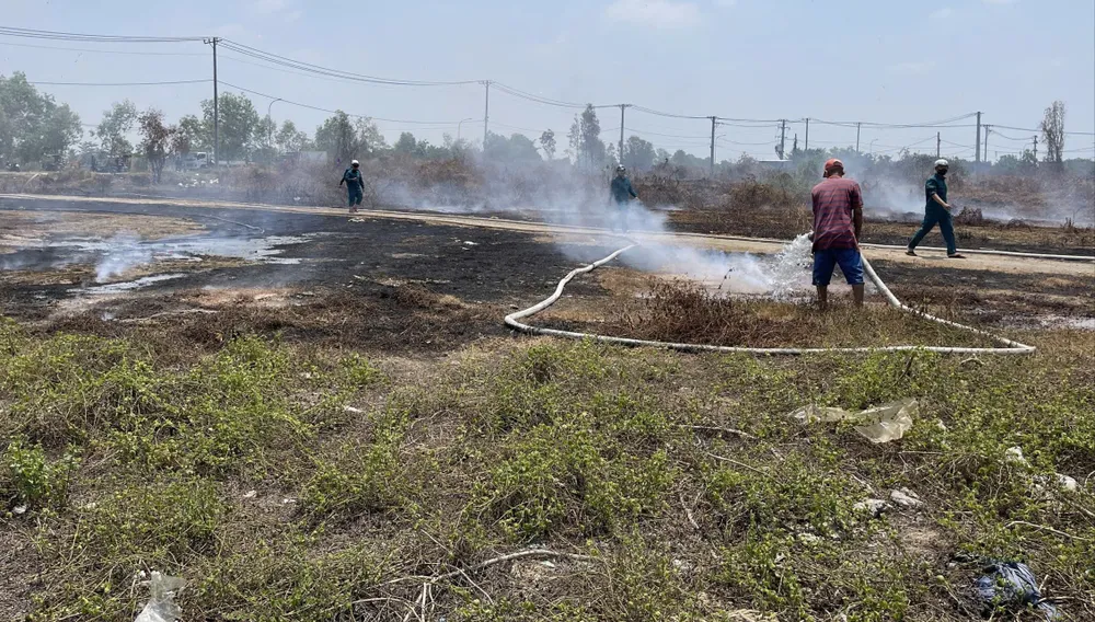 Lực lượng chức năng xã Tân Vĩnh Lộc đang khống chế đám cháy do các đối tượng đốt rác gây cháy lan tại khu đất trống trên đường Trần Hải Phụng, xã Tân Vĩnh Lộc. Ảnh: TK