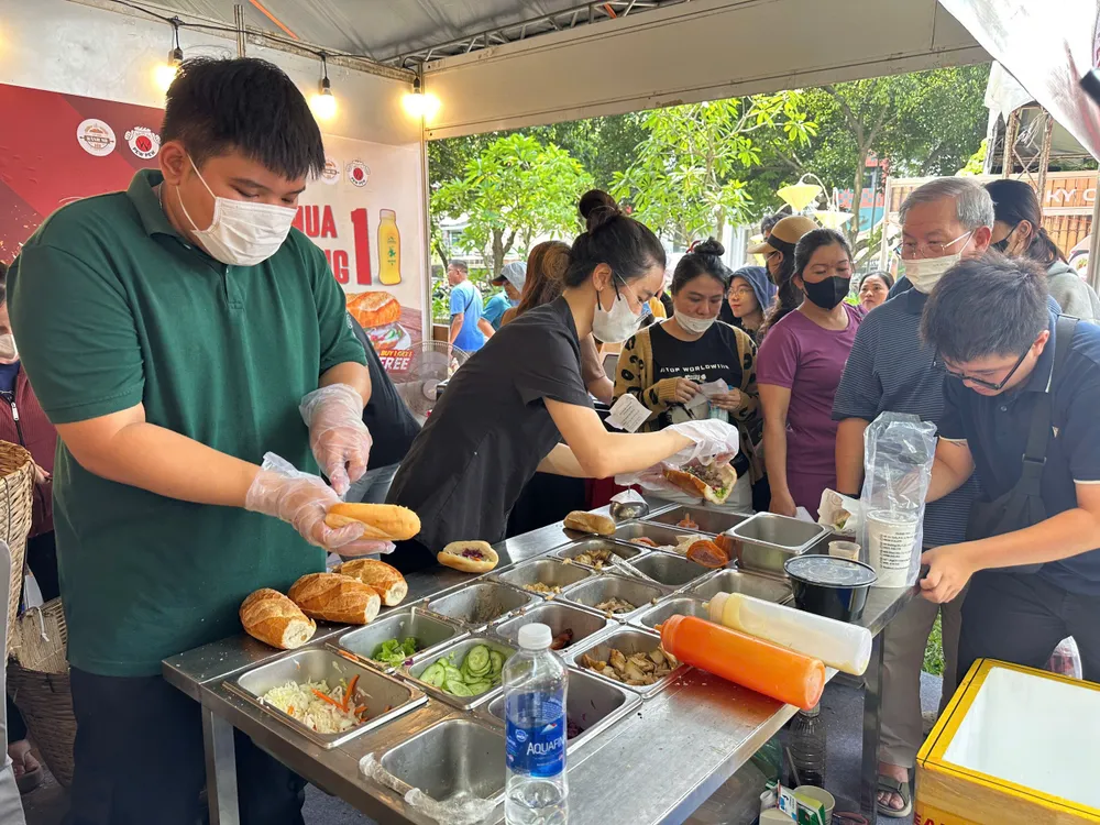 Người dân xếp hàng mua và thưởng thức bánh mì trong chiều và tối 21-3, tại công viên Lê Văn Tám