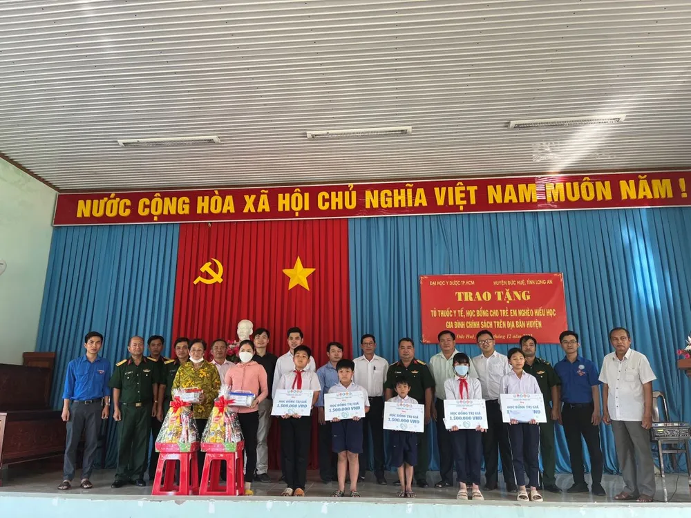 Lãnh đạo Bộ Chỉ huy Quân sự tỉnh Long An cùng Trường Đại học Y Dược TPHCM trao quà, học bổng và tủ thuốc y tế tại huyện Đức Huệ. Ảnh: TRẦN YÊN