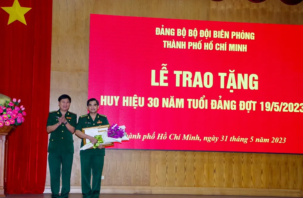 Đại tá Trần Thanh Đức trao huy hiệu 30 năm tuổi Đảng và tặng hoa chúc mừng đồng chí Tô Danh Út