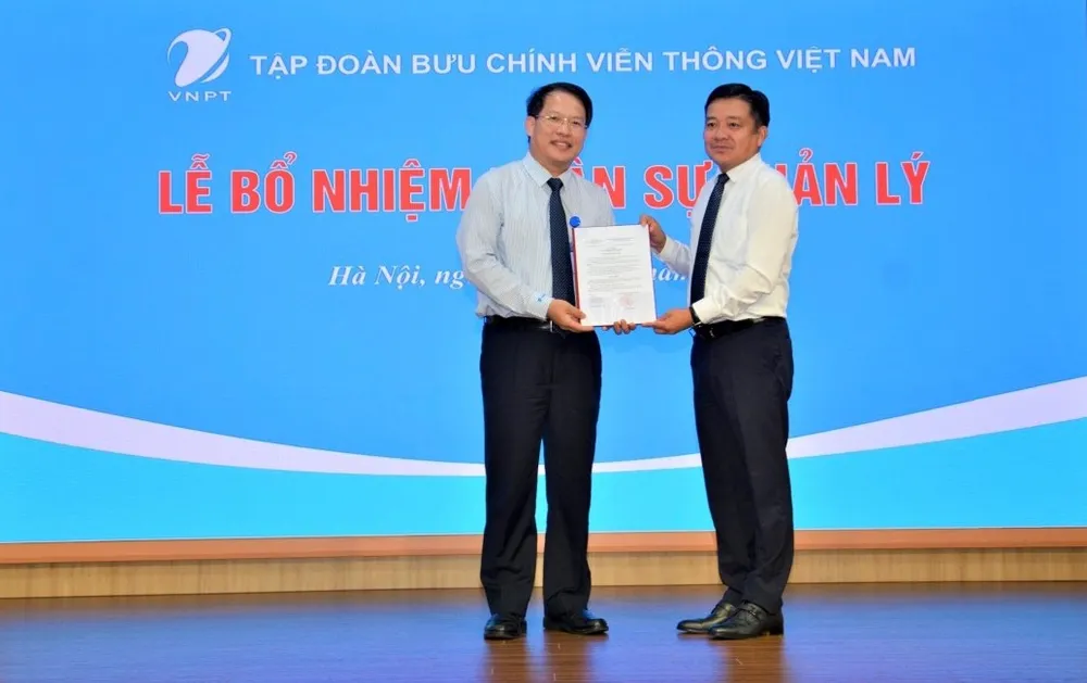 Tổng Giám đốc Tập đoàn VNPT Huỳnh Quang Liêm (bên phải) trao quyết định bổ nhiệm cho tân Tổng Giám đốc VNPT VinaPhone Nguyễn Văn Tấn