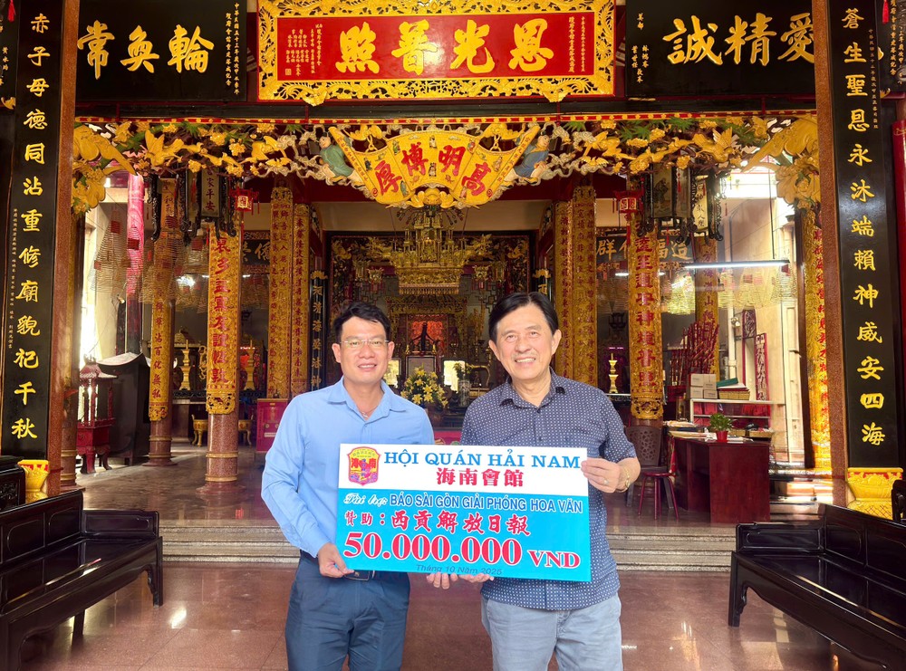 海南会馆理事长林明辉（右）向《西贡解放报》执行编辑文忠孝（左）移交5000万元赞助经费。