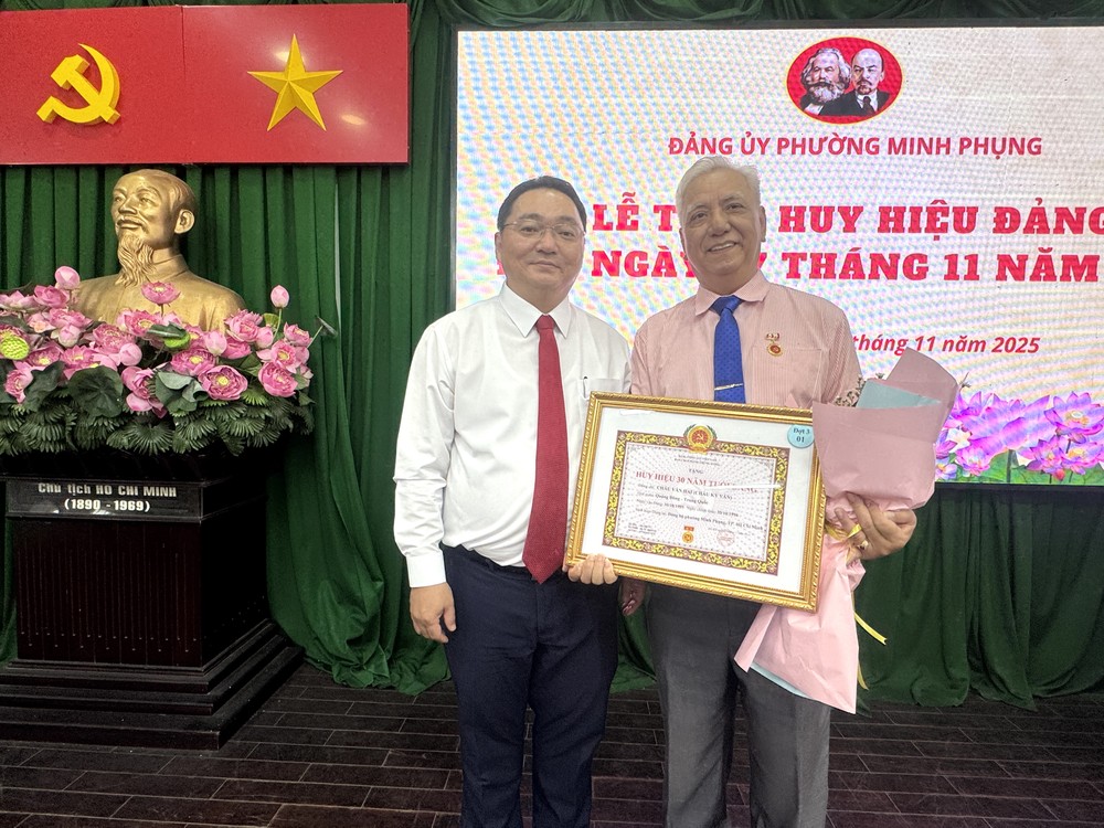 鸣凤坊党委书记、人民议会主席阮陈平祝贺华人退休干部朱杞文获30年党龄纪念章。