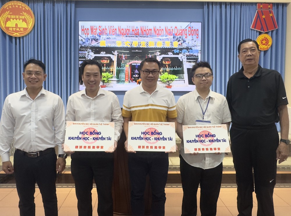 《西贡解放报》执行编辑文忠孝（左一）与穗城会馆常值副理事長林海泉（右一）向大学生颁发鼓励金。